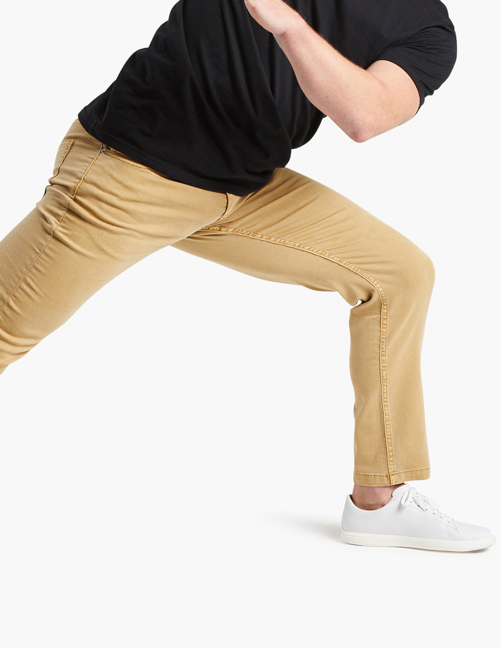 Person wearing tan pants and white sneakers in a wide stance pose