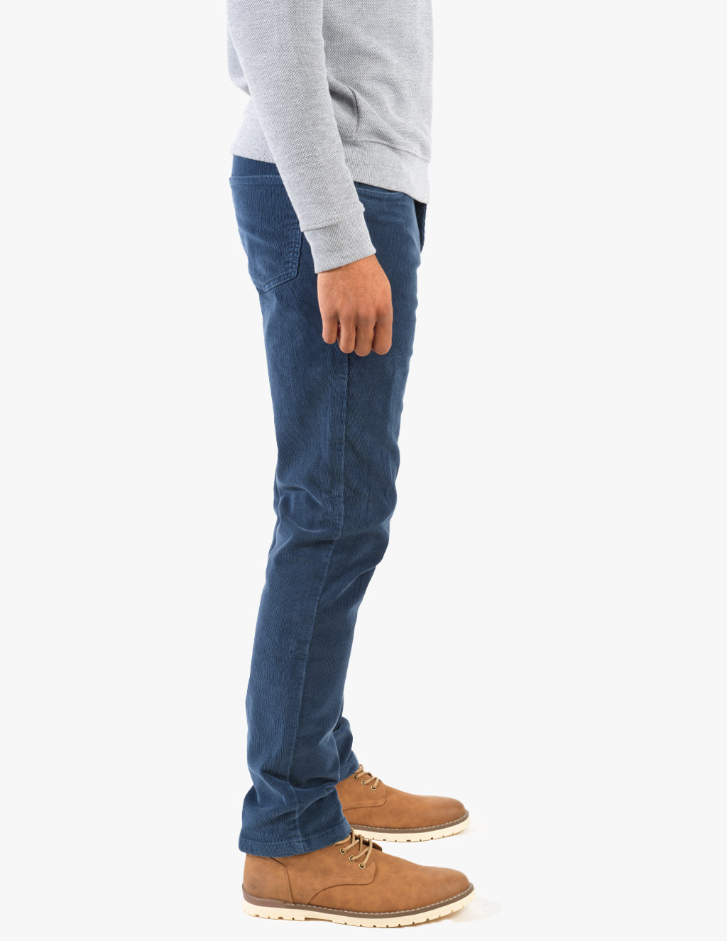 Side view of person wearing blue corduroy pants and tan lace-up boots with grey sweatshirt sleeve visible.