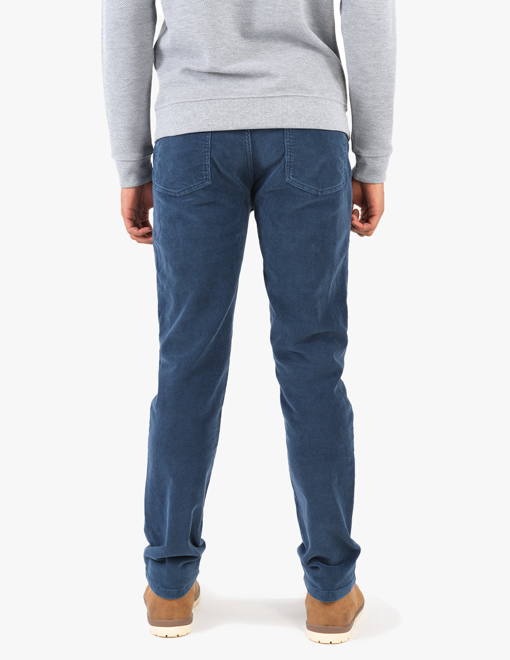 Back view of a person wearing blue corduroy pants, a grey sweatshirt, and tan boots.