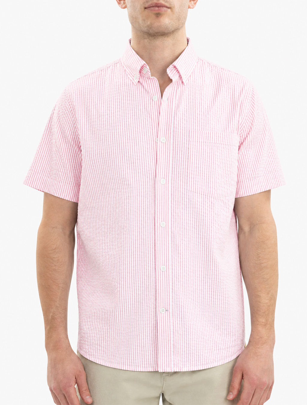 Front view of pink seersucker short-sleeve shirt on model showing vertical stripes and chest pocket on white background
