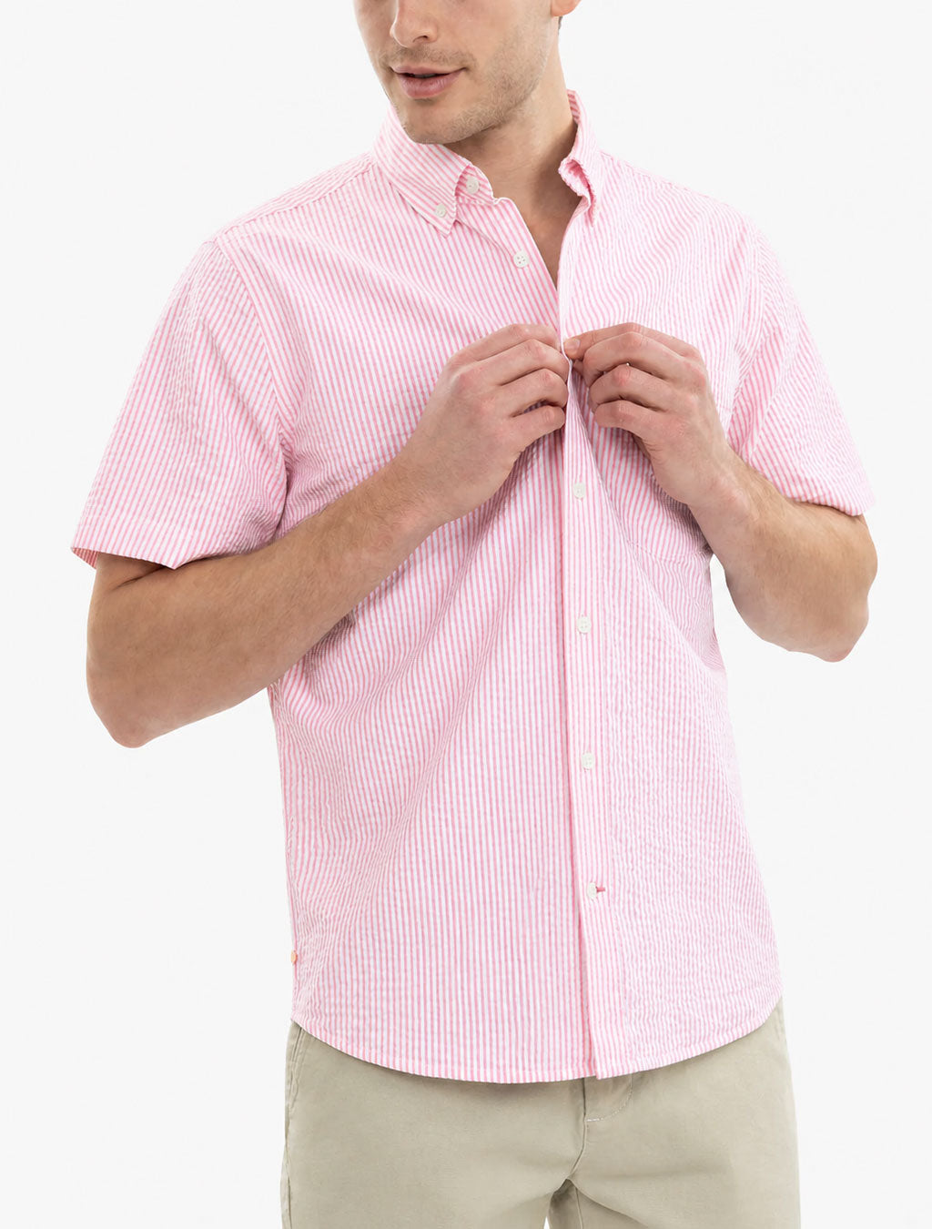 Front view of pink seersucker short-sleeve button-up shirt on model, showing textured stripe fabric and button-down collar against white background