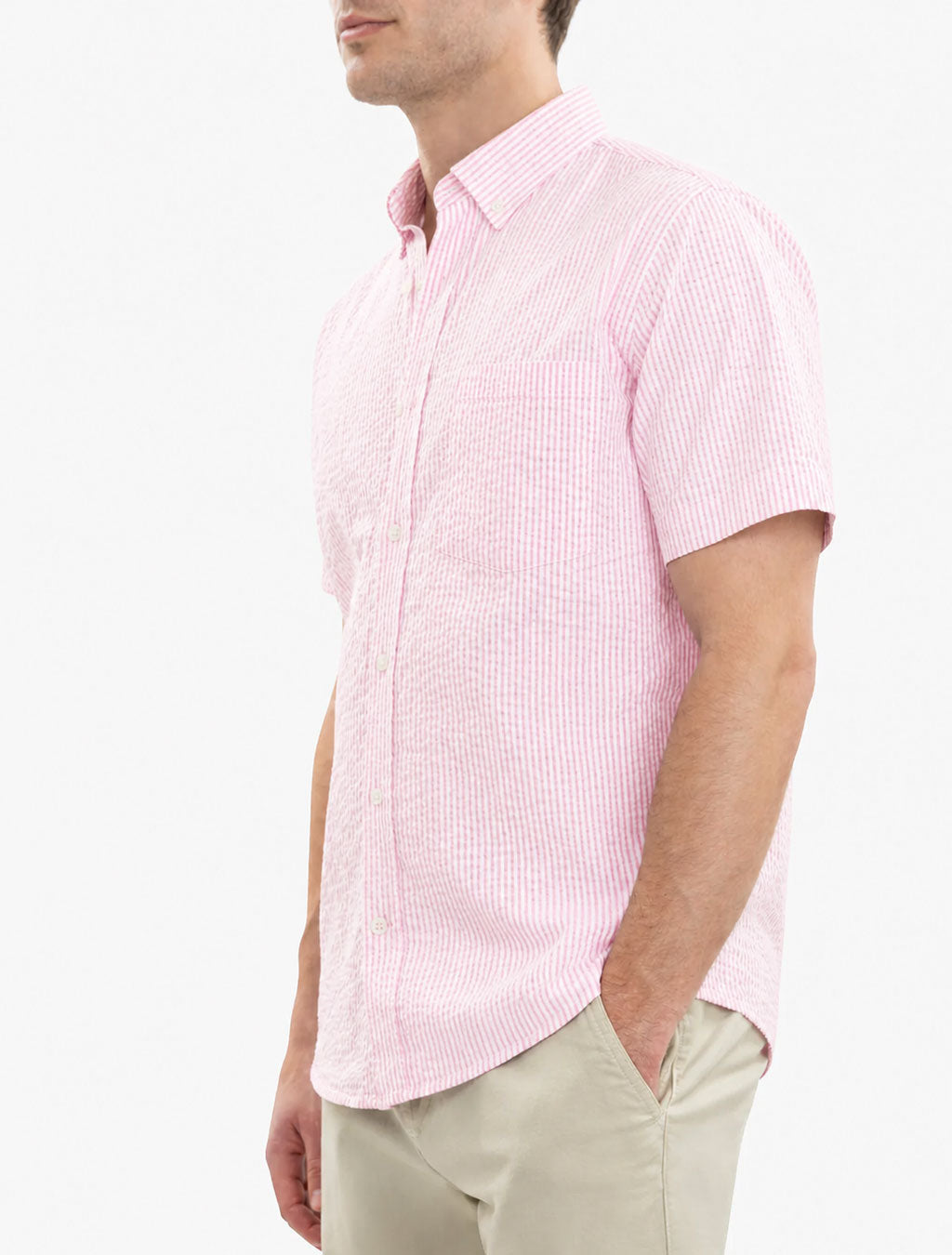 Three-quarter side view of pink seersucker short-sleeve button-down shirt on model showing textured stripe fabric and chest pocket on white background