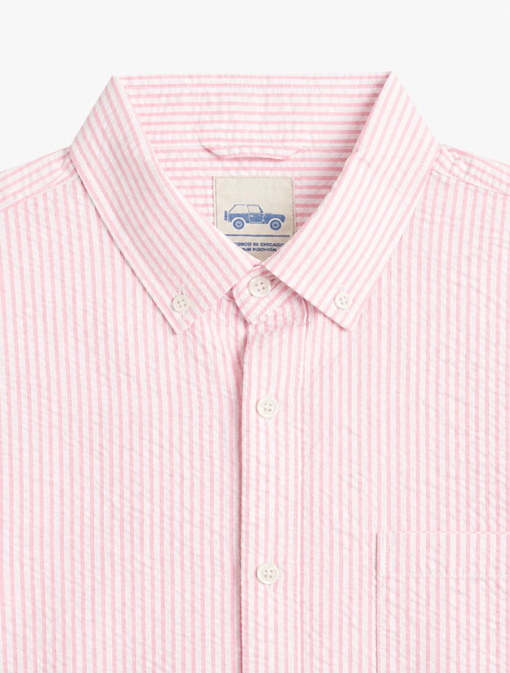 Close-up front of pink seersucker shirt showing button-down collar, white buttons, and chest pocket on white background