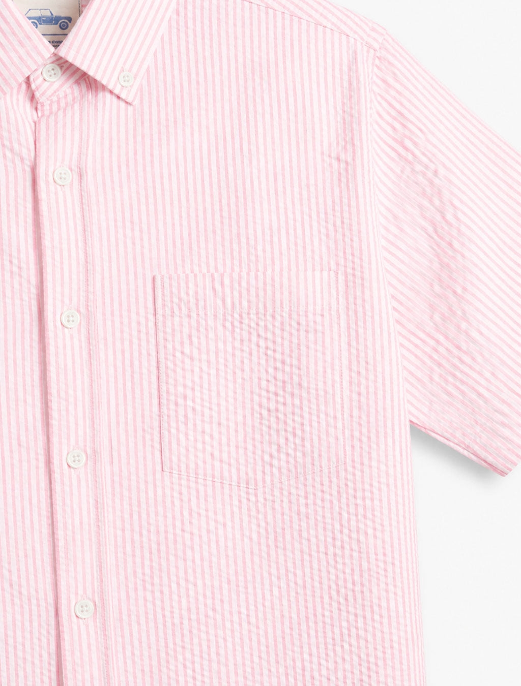Front close up of pink seersucker short sleeve shirt showing textured pink and white stripes and chest patch pocket