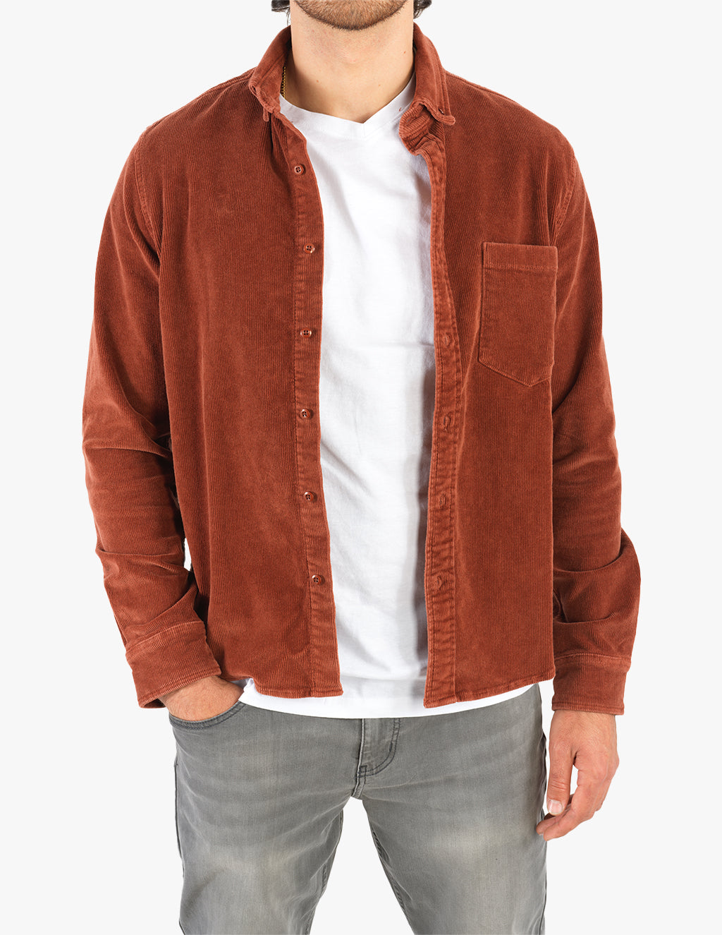 Male torso wearing open rust corduroy shirt over white T-shirt and faded gray jeans, hands partially in pockets.