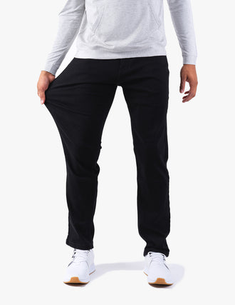 Front view of Squid Inks Casual jeans in black showcasing fabric stretch as model pulls the thigh, white background