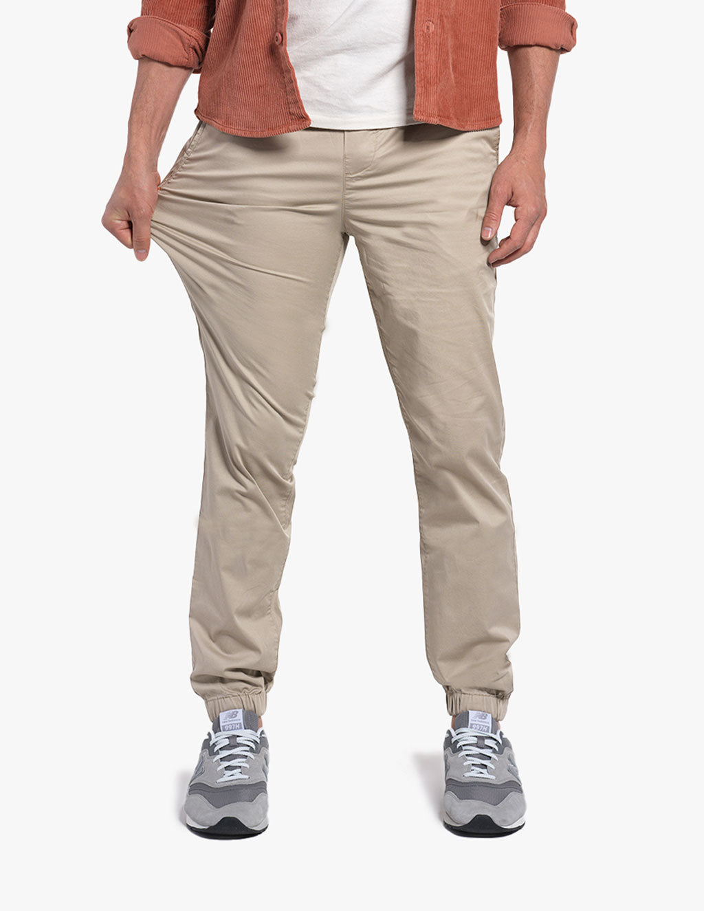 A person wearing beige joggers, stretching the fabric to show flexibility.