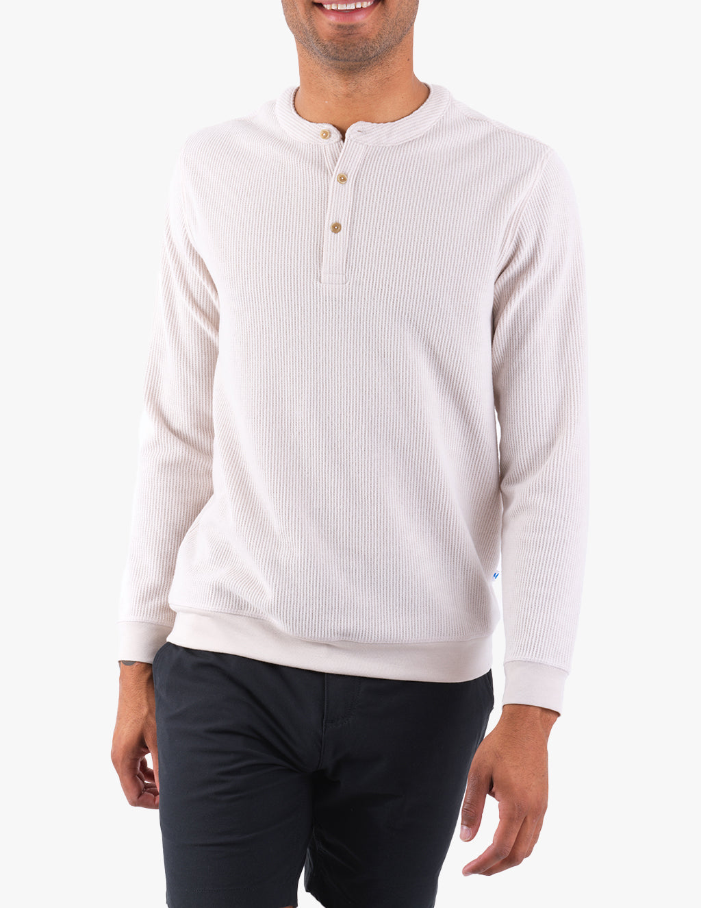 A person wearing a light-colored henley shirt with buttons, standing against a white background.