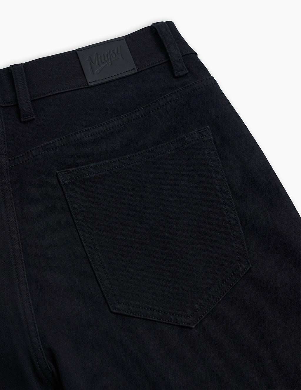 Black denim back pocket and waistband with leather brand patch reading Mugsy.