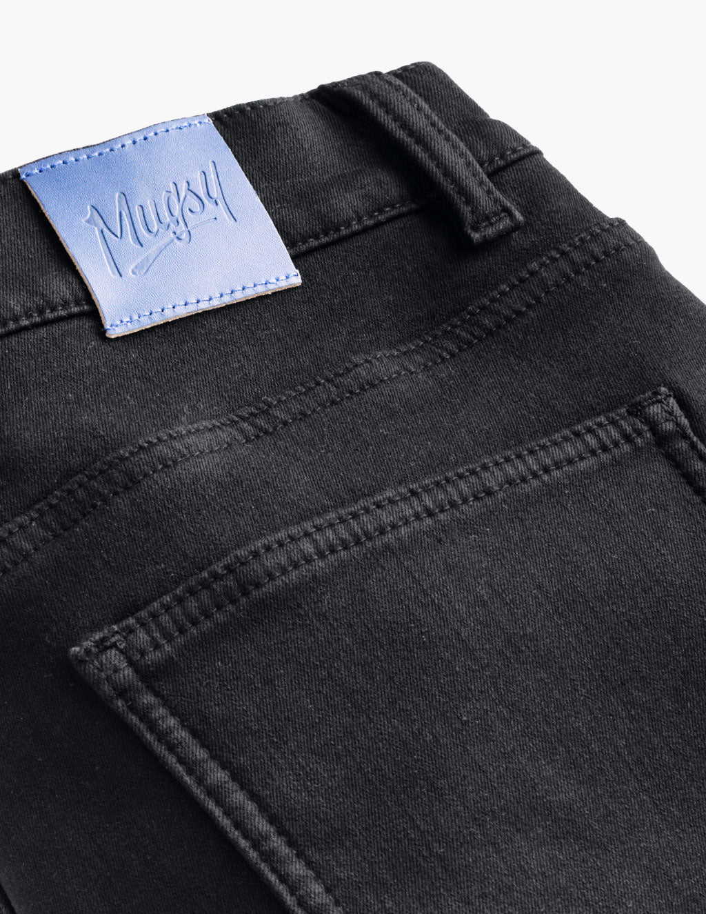 Back pocket and waistband of black jeans with blue leather brand patch reading 'Mugsy'.