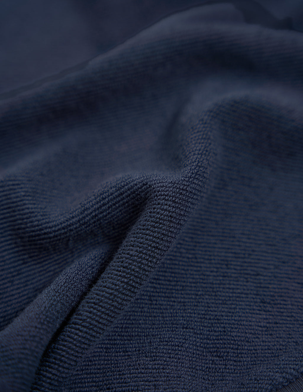 Close-up of navy blue knitted fabric showing ribbed texture and folded drape.