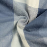 Close-up of blue and white plaid woven wool fabric twisted into a swirl, showing twill weave and soft texture.