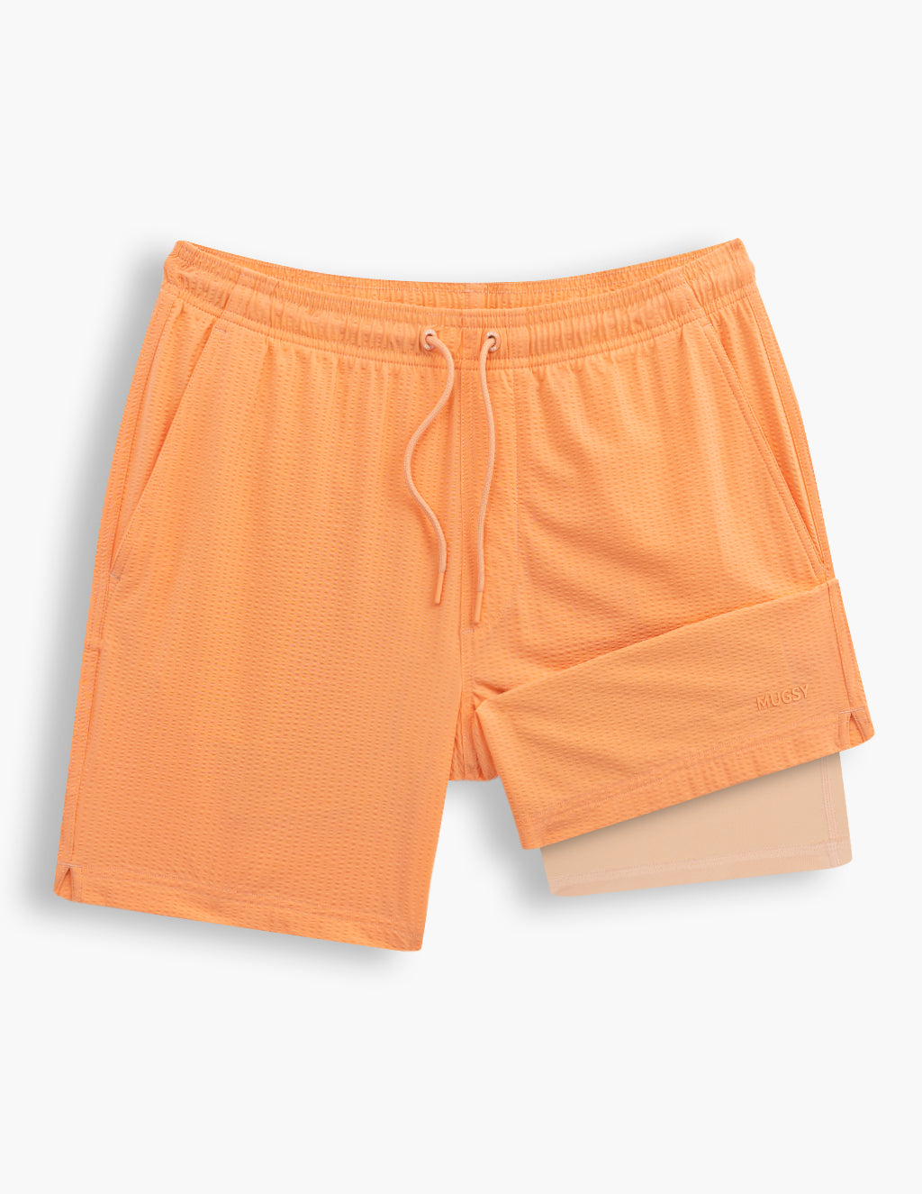 Flat lay of coral men's swim shorts showcasing textured fabric, drawstring waistband, side pockets, and inner liner on white background