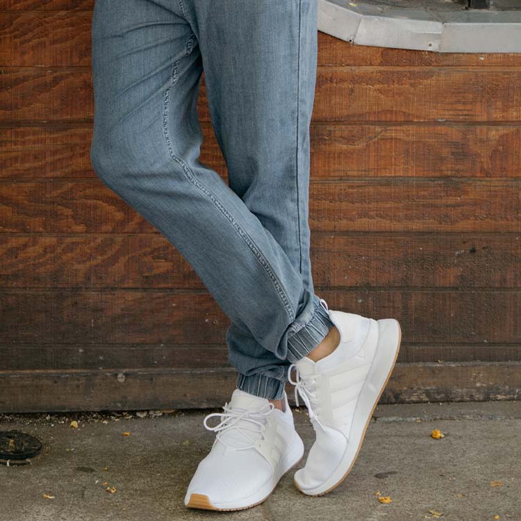 Model wearing light blue joggers and white sneakers, showcasing comfort and style.