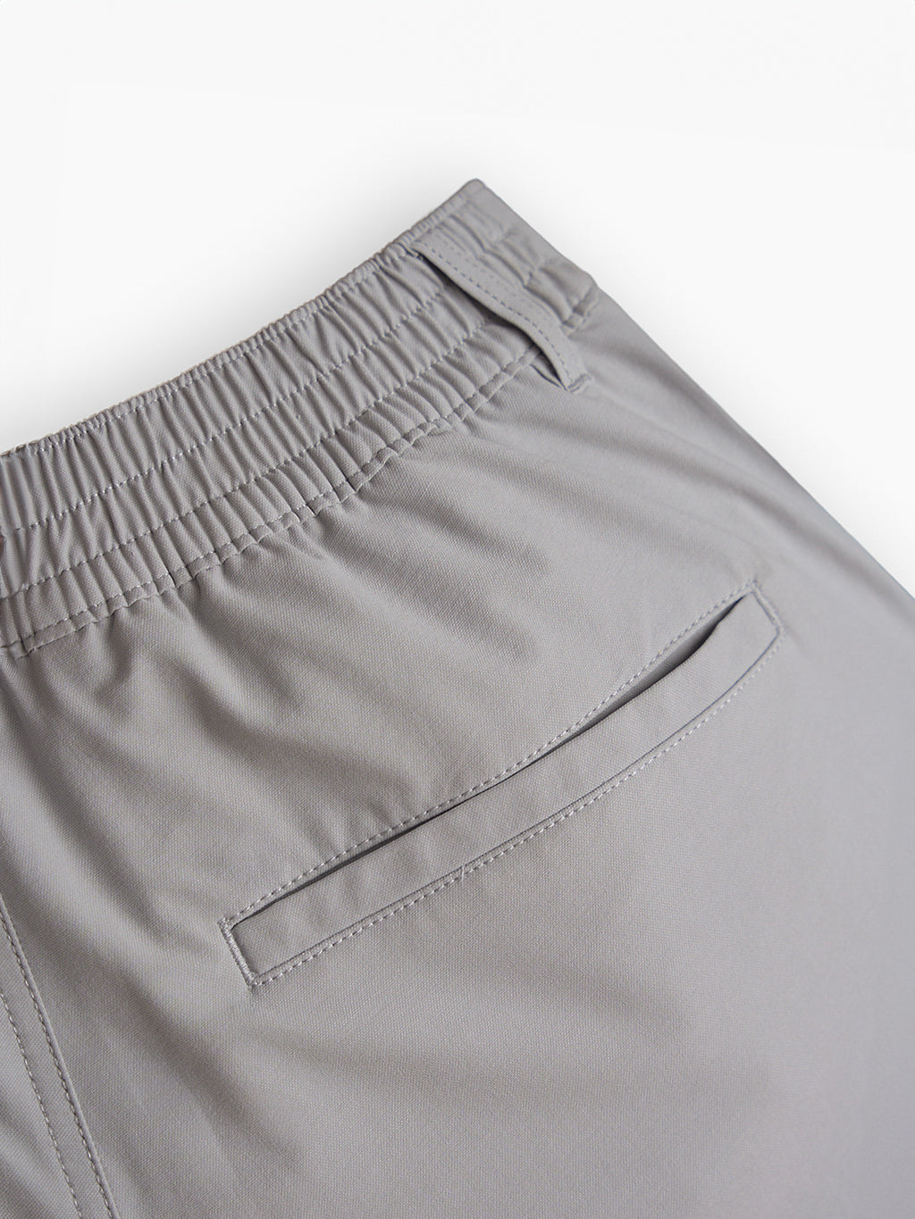 Close-up of gray pants showing elastic waistband and back pocket detail.