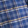 Blue and yellow plaid flannel shirt close-up showing chest pocket with two dark buttons