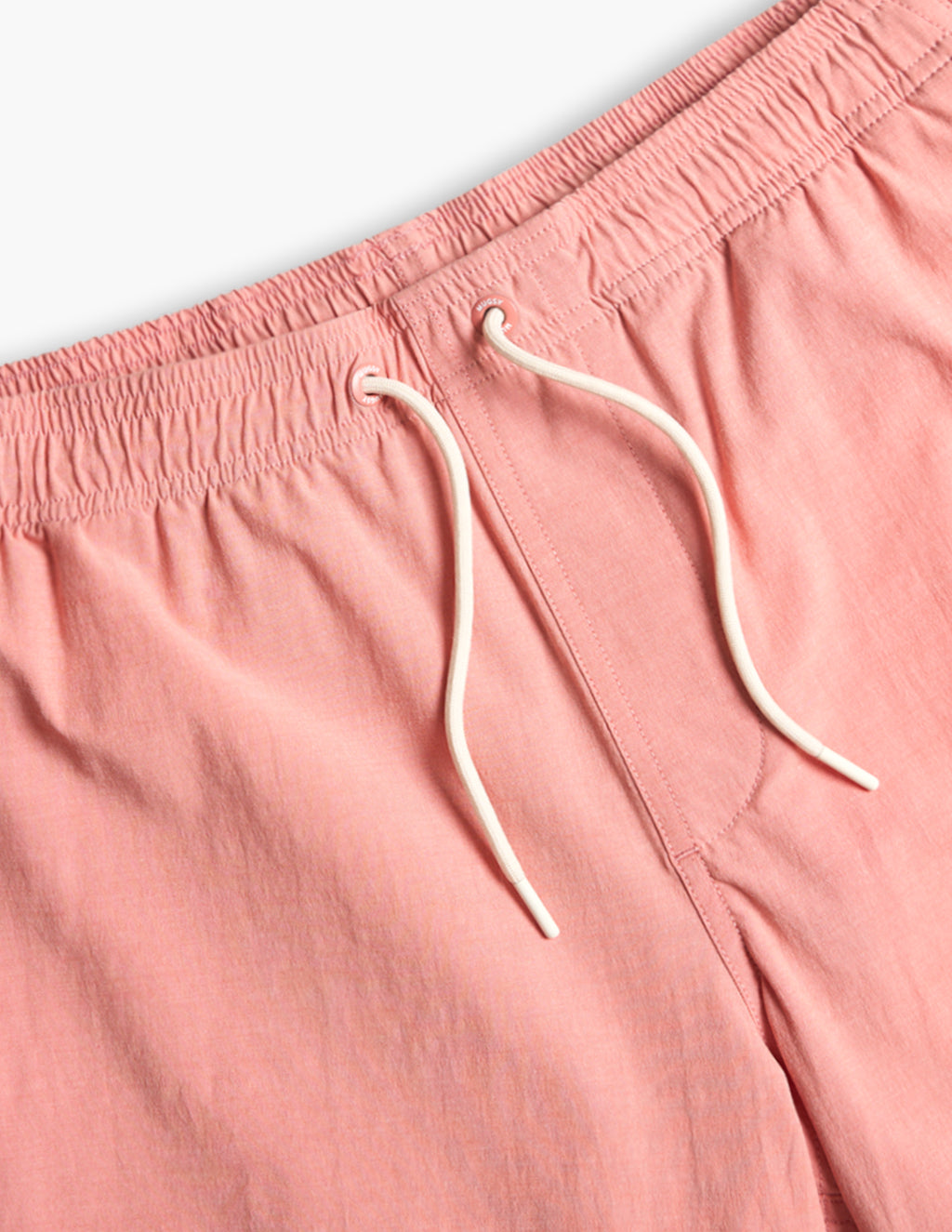 Close-up of pink shorts with an elastic waistband and white drawstring cords.