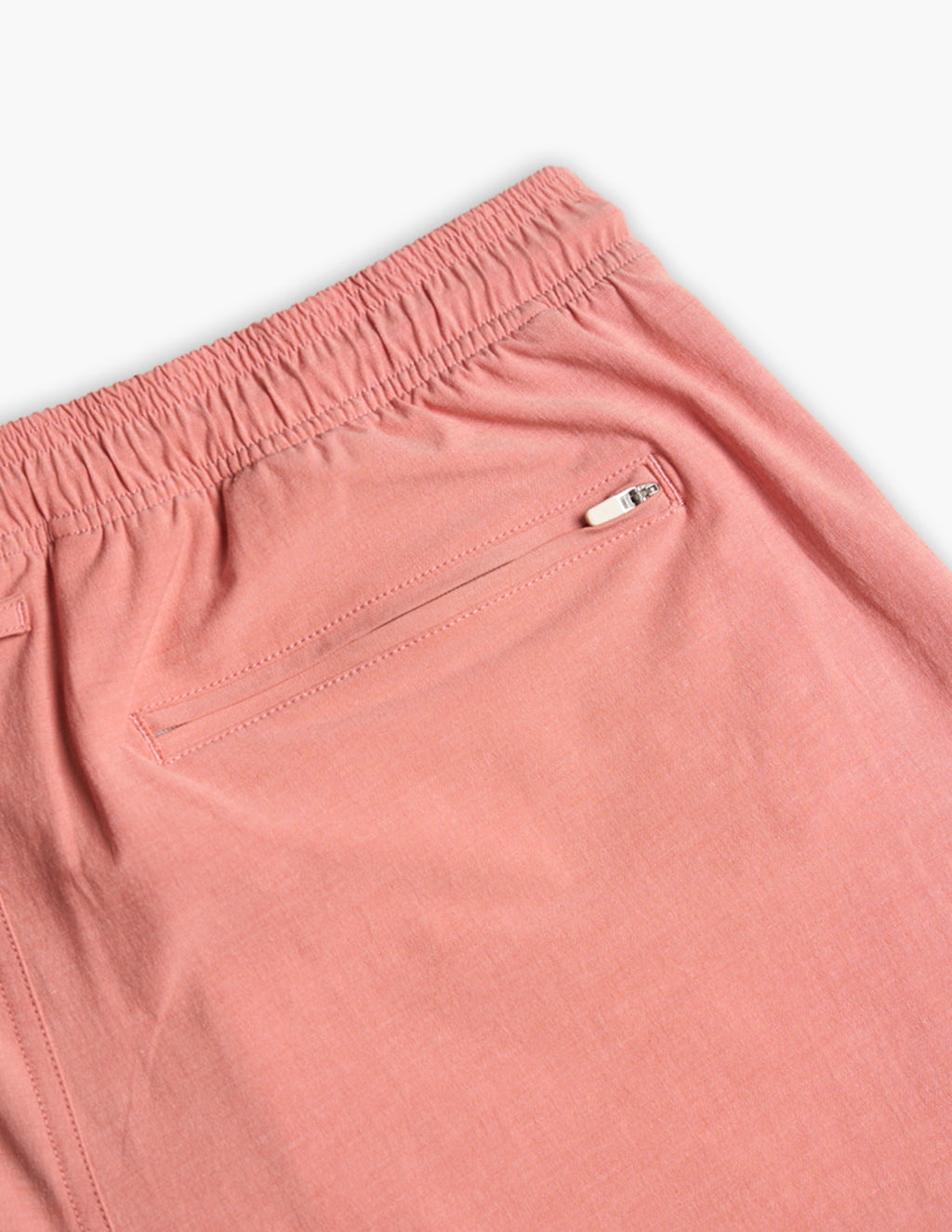 Close-up of a pink garment showing an elastic waistband and a zippered back pocket