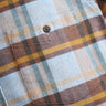 Close-up of brown, light blue and yellow plaid flannel shirt pocket with stitched flap and brown button