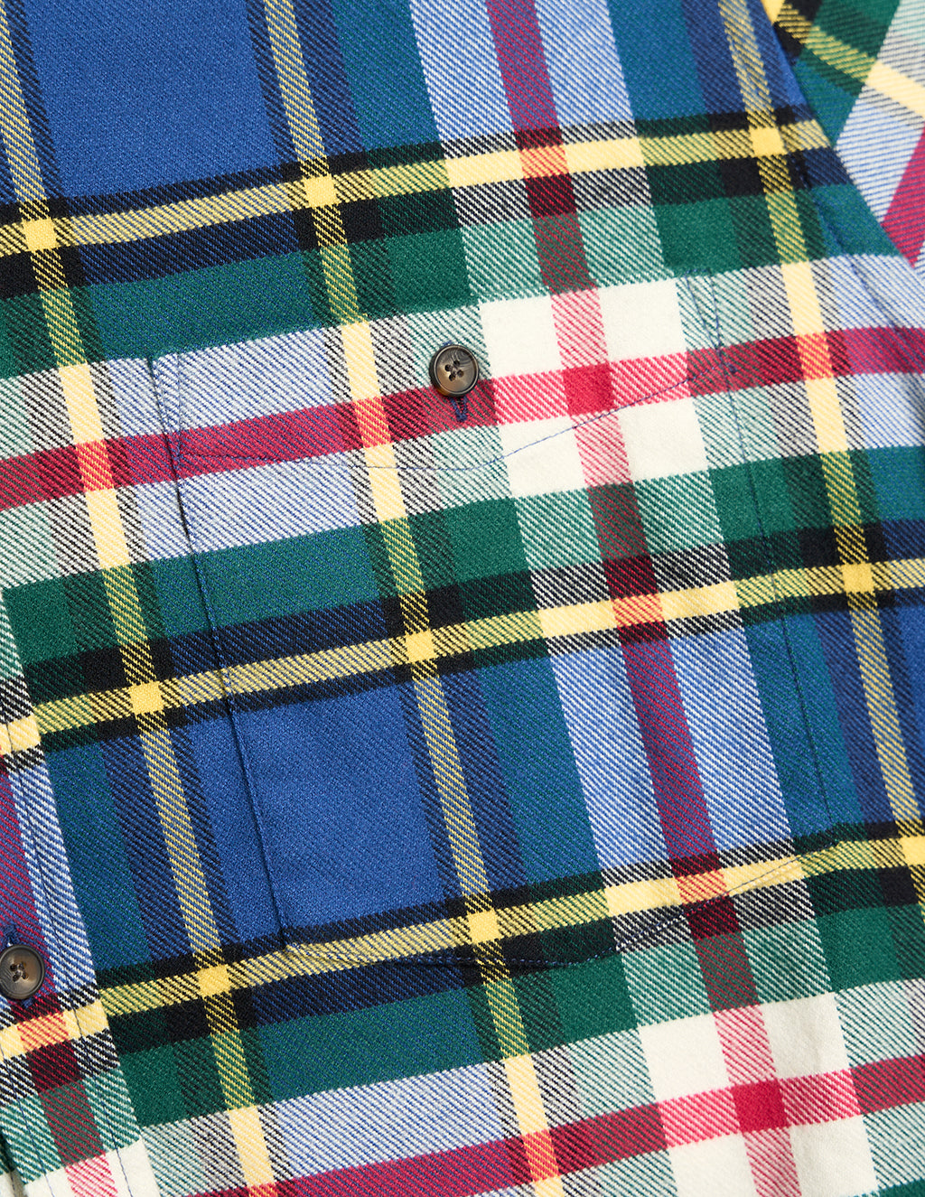 Close-up of a green, blue, red, and yellow tartan flannel shirt pocket with a dark brown button