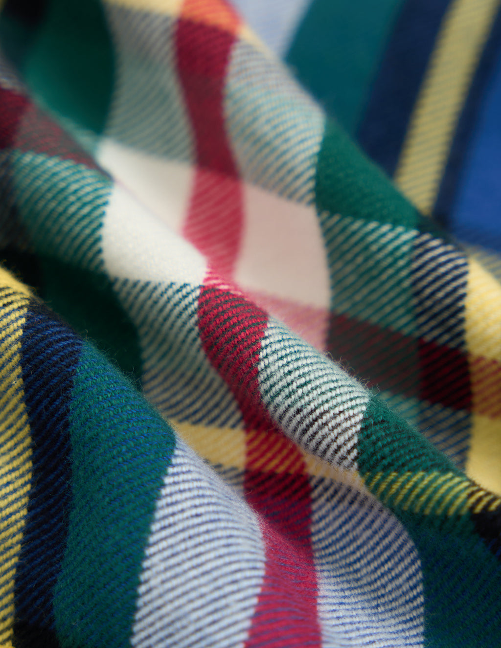 Brushed wool plaid fabric with green, red, yellow and navy stripes and visible diagonal weave texture.