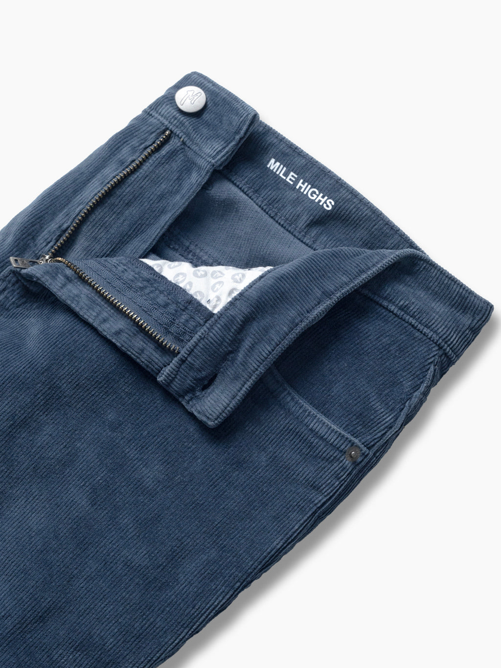 Navy corduroy pant waistband with open zipper revealing patterned pocket lining and 'MILE HIGHS' label