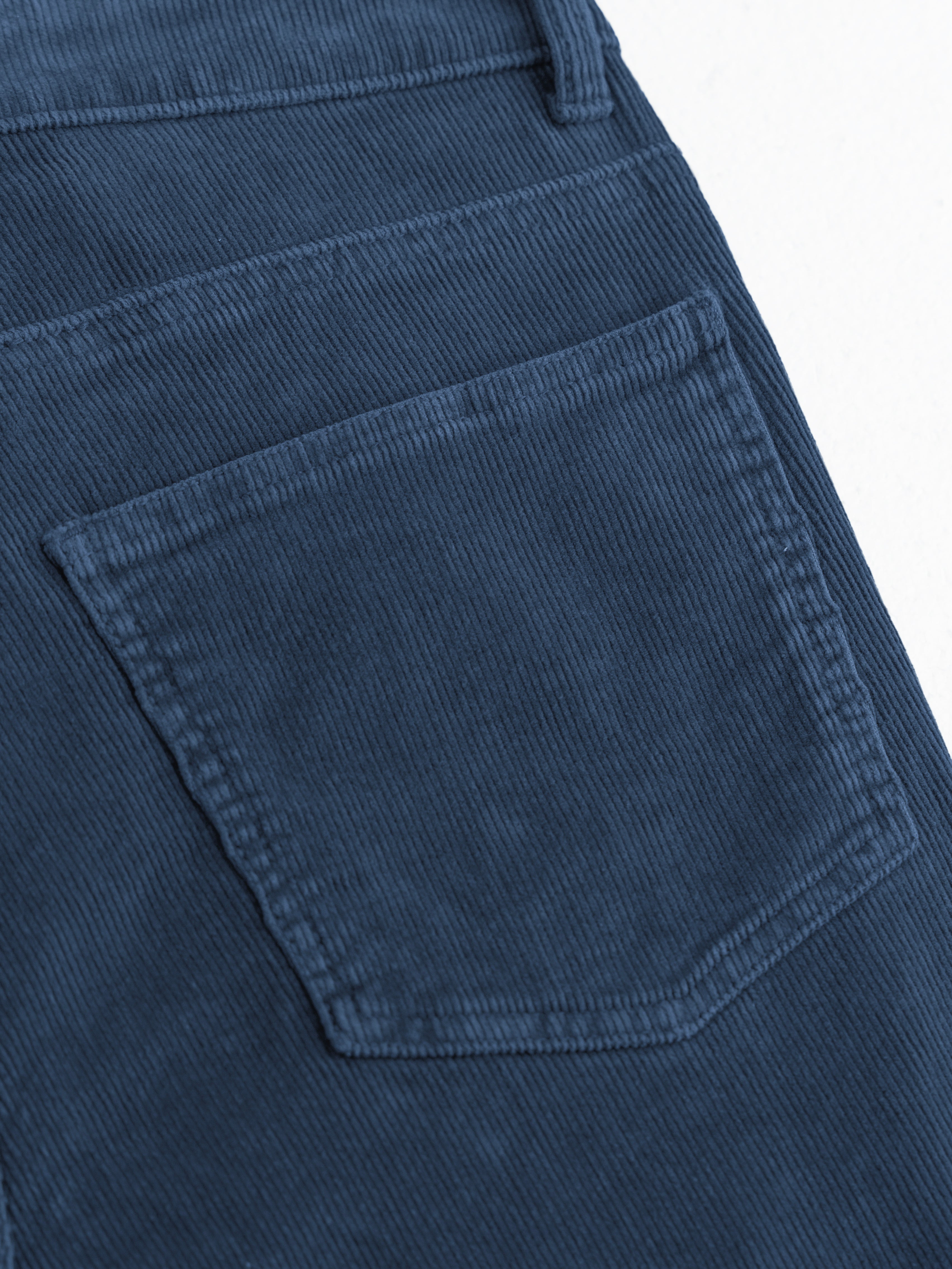 Blue corduroy back pocket, close-up showing vertical ribs and topstitching.