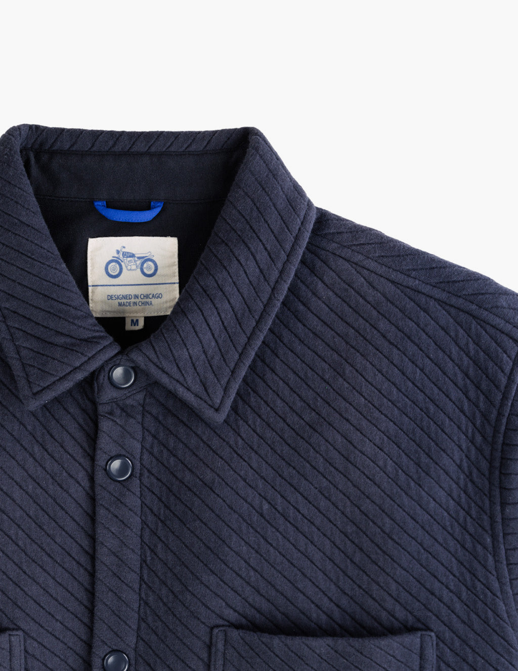 Close-up of navy Diamond Knit Shacket showing collar, snap buttons, chest pocket, and diagonal quilted texture