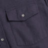 Dark navy wool shirt close-up showing flap pocket with button and visible stitching.