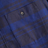 Blue and navy plaid shirt close-up showing buttoned chest pocket and textured fabric