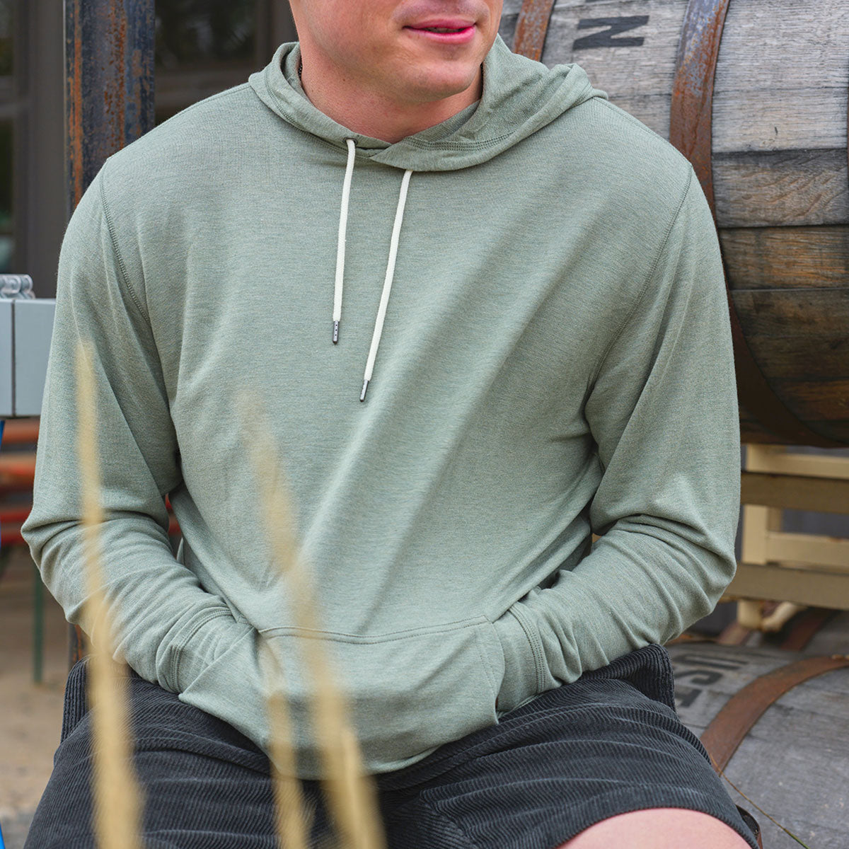 A man wearing a green hoodie, sitting outdoors.