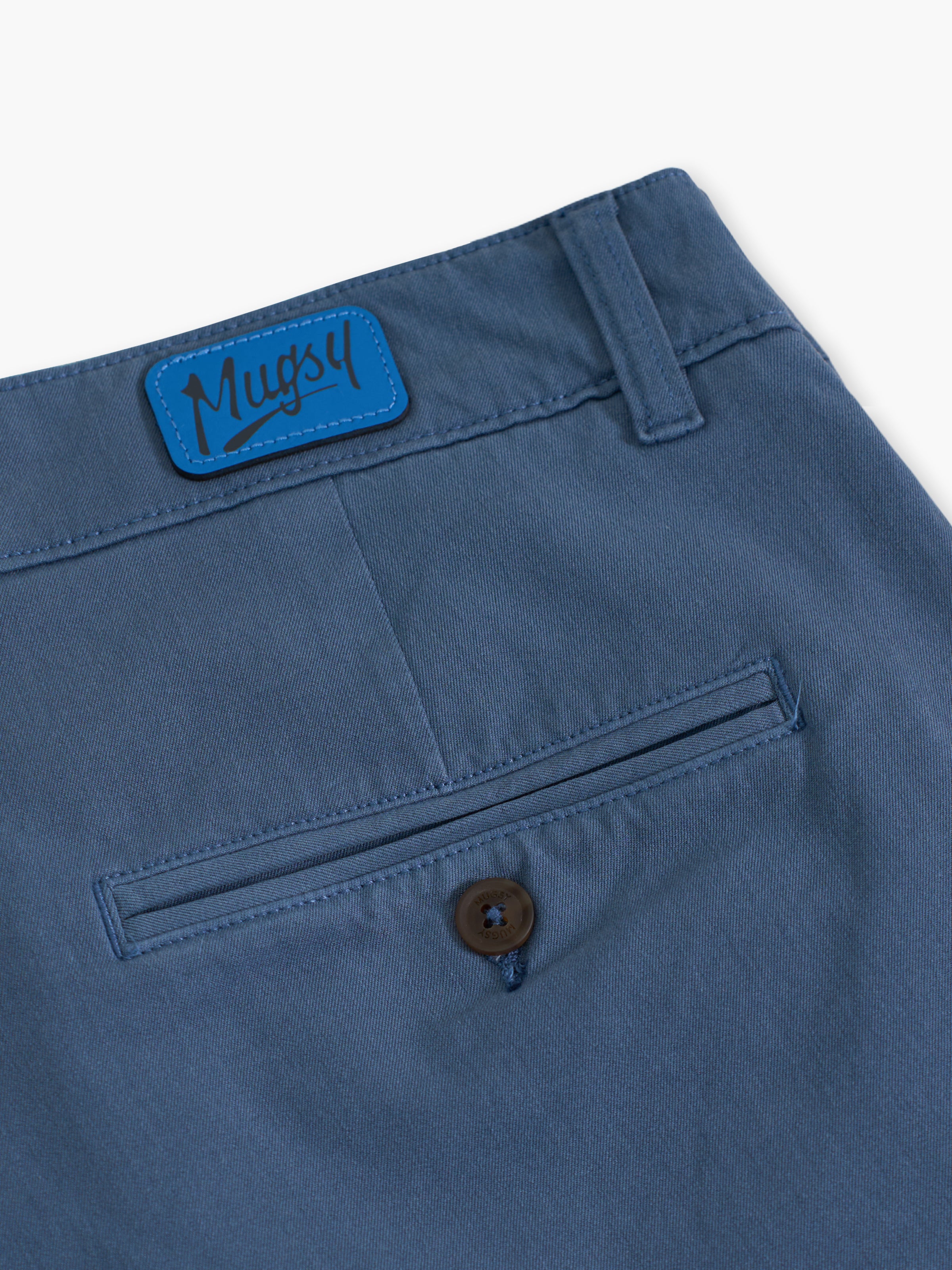 Back closeup of Saltwaters chinos showing a welt pocket with button, belt loop, and blue Mugsy logo patch on white background