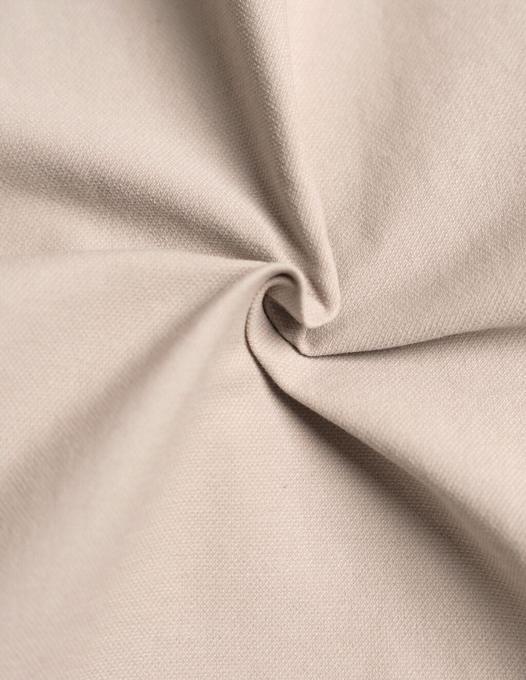 Beige woven fabric close-up with a twisted center fold and visible textured weave.