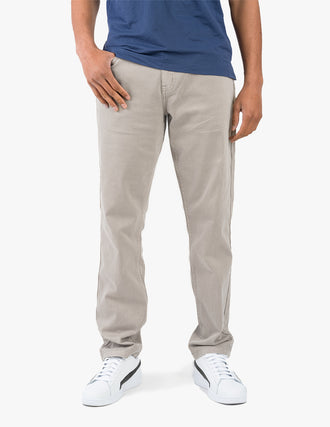 A person wearing light tan Bucks Casual pants, standing with one hand in pocket.