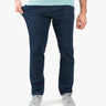 Model wearing dark blue casual stretch jeans, pulling left thigh to show fit; mint T-shirt hem and gray sneakers visible