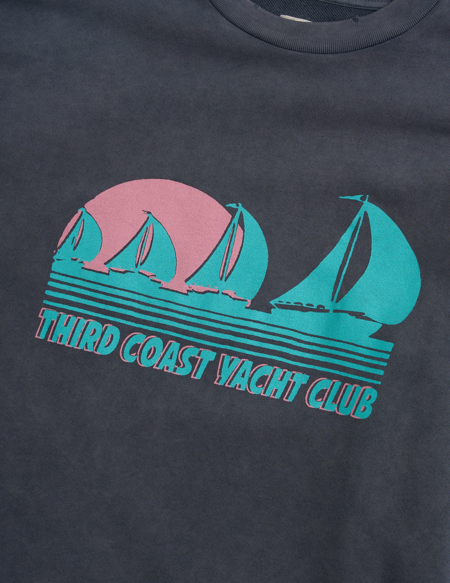 Dark-gray T-shirt graphic of three teal sailboats with pink sun above and striped water, text 'THIRD COAST YACHT CLUB'.