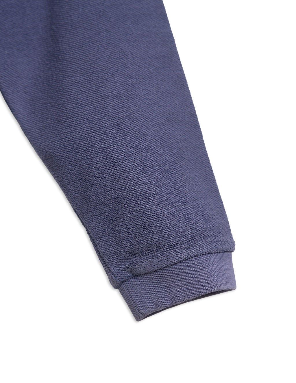 Purple indigo sweatshirt sleeve close-up with ribbed cuff and textured knit fabric
