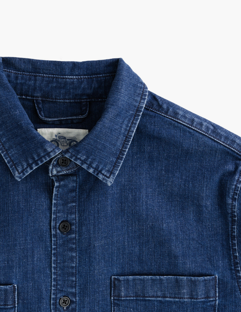 Close-up front view of Wyatts denim button-down shirt showing collar, top three buttons, and chest pocket on white background