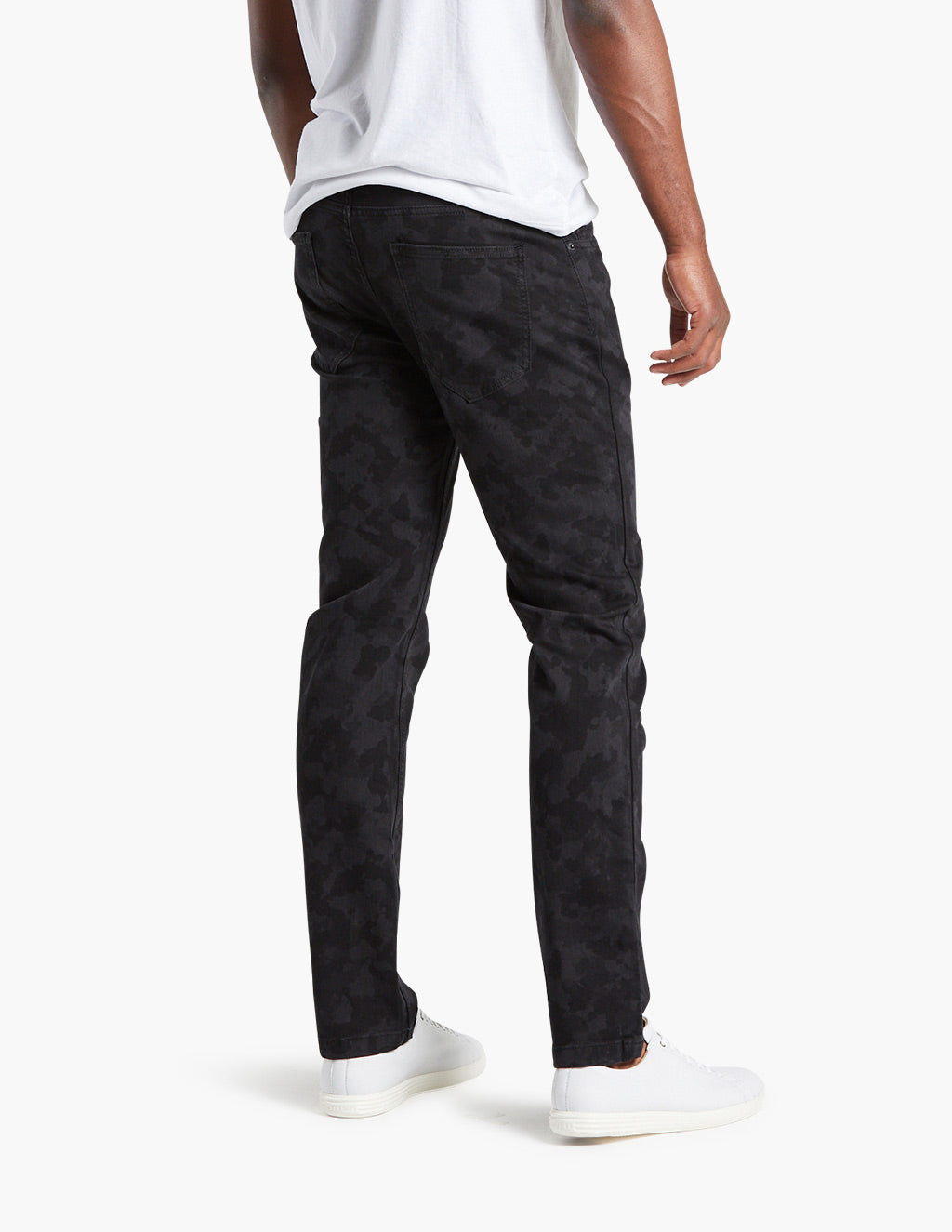Black camo jeans worn by a model, showcasing the back view.