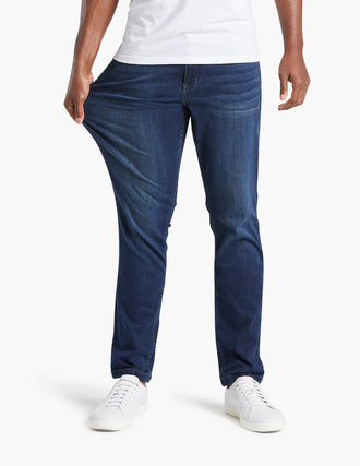 Front view of men's Classic Fultons jeans showcasing dark blue stretch denim and straight fit as model pulls fabric, white background