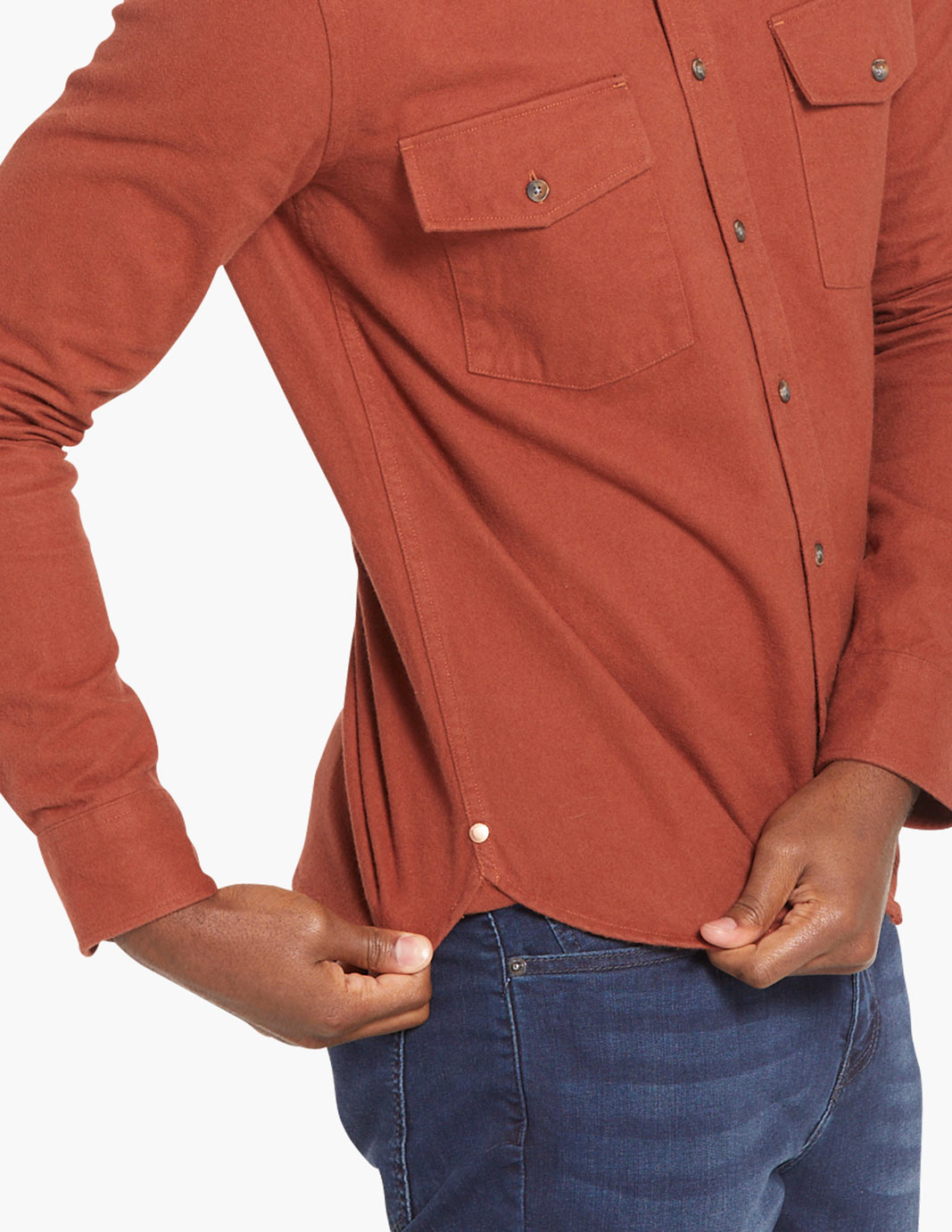 Model wearing a burnt orange stretch heavy flannel shirt, adjusting the hem.