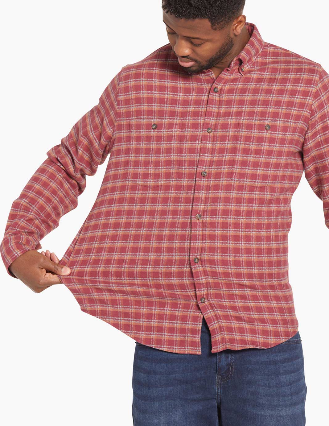 Model wearing a red and orange plaid flannel shirt, showcasing its stretch fabric.
