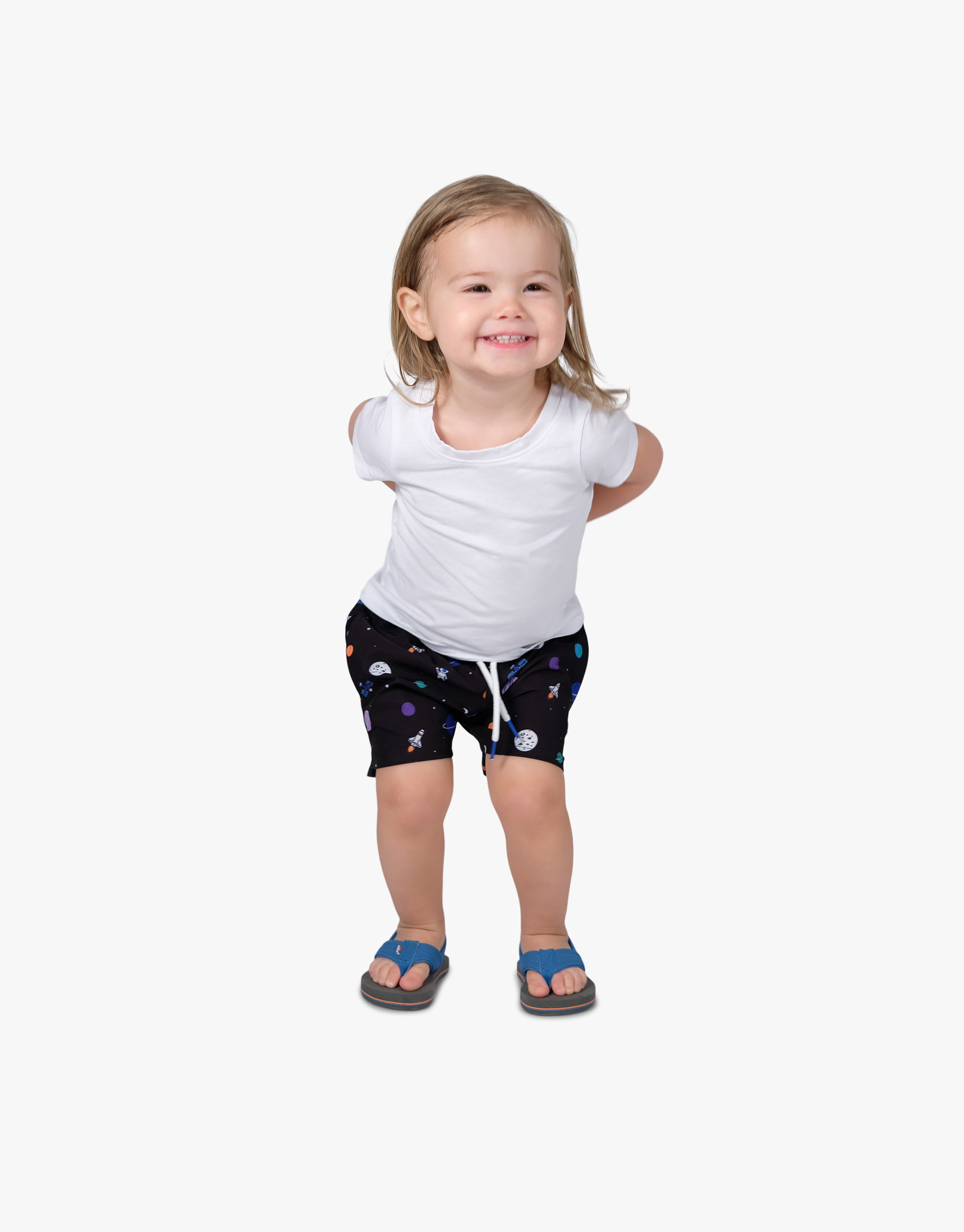 A child wearing a white shirt and black swim shorts with colorful space-themed designs.