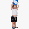 Child holding a beach ball, wearing black swim shorts with colorful patterns.